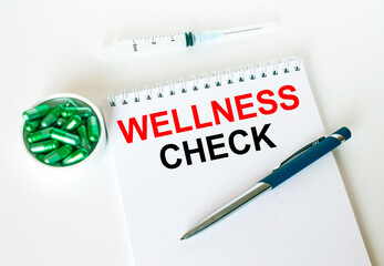 Obraz premium Text Wellness Check written in a notebook with a blue pen and a bunch of pills