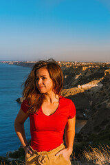 Happy young woman with long hair on vacation on the edge of the cliff of Cape Fiolent in Crimea, beautiful view of the Black sea