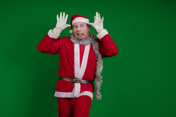 Male actor in a costume of Santa Claus gesturing and posing on a green chroma background