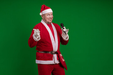 Male actor in a costume of Santa Claus holds a microphone in his hands, sings and poses on a green background - Powered by Adobe