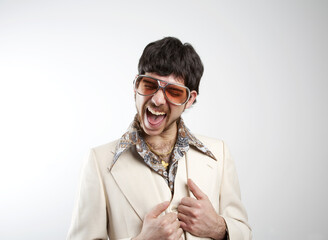 Portrait of a retro man in a 1970s leisure suit and sunglasses smiling to the camera - excited