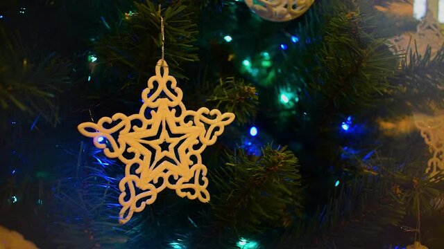 Christmas Tree Decorations. Beige plastic christmas star on fir tree pan shot. Christmas tree decorated with a star, balls and other decor. Blinking Garland. Christmas Tree Lights Twinkling.