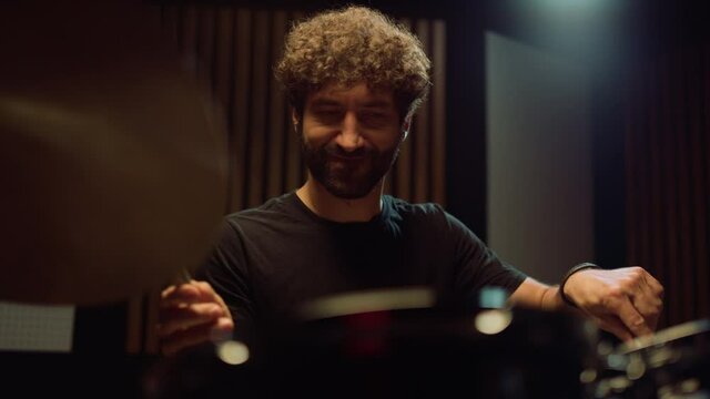 Smiling drummer having fun in studio. Musician playing on drum cymbals indoor.