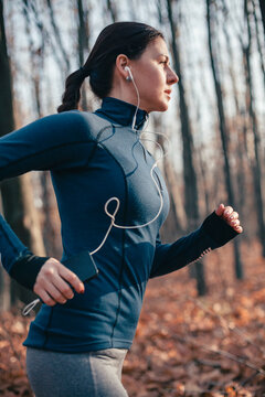 Caucasian woman listening to earbuds while running