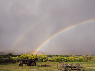 Double rainbow after storm over rusty tractor and wagon