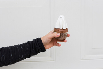 Little girl holding Halloween cupcakes