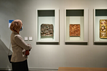 woman stading in a room looking and pointing at the empty frames displayed