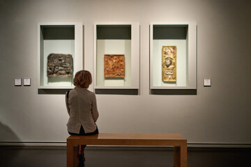 woman stading in a room looking and pointing at the empty frames displayed