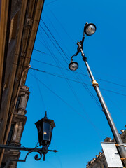 Fototapeta na wymiar Old vintage black dark glass street lamp hanging on textured wall of beautiful building and lantern post, pillar in city of Saint Petersburg. Blue sky gradient. Contrast