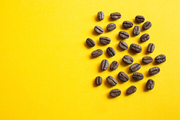 Coffee beans close-up on a bright yellow background with copy space