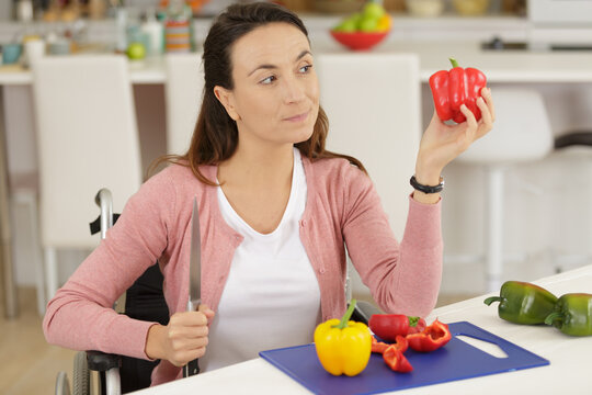 disabled woman in wheelchair preparing meal in kitchen