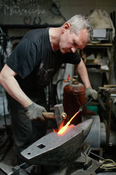 Caucasian adult male blacksmith working with metal