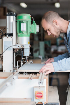 Young carpenter working on a hinge boring machine