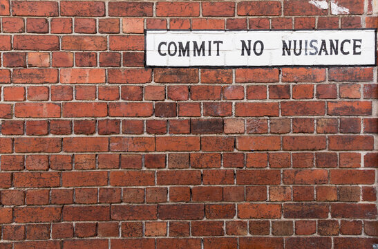 Vintage sign on red brick wall - Commit No Nuisance