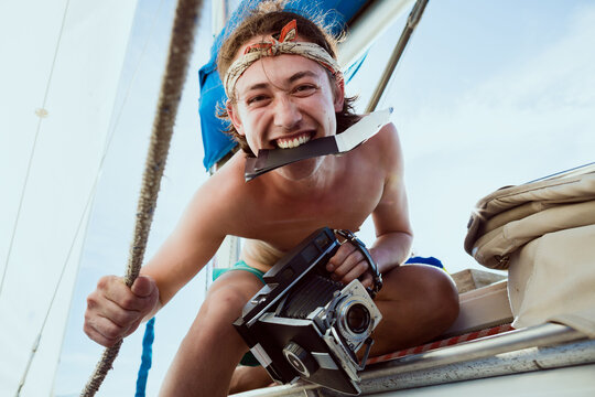 A young pirate smiles on the edge of a sailboat through Rio's harbors