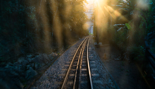 Sun flare peaks out on the tracks of a railroad