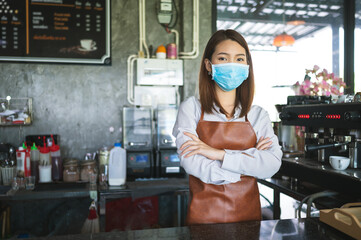 Fototapeta na wymiar New normal startup small business Portrait of Asian woman barista wearing face mask working in coffee shop while social distancing.