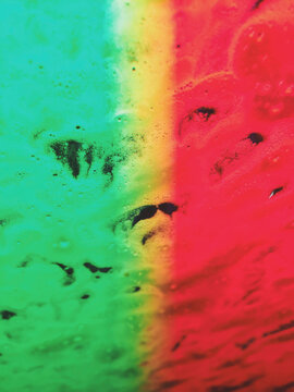 Close of soapy water on car windshield with green, yellow and red lighting