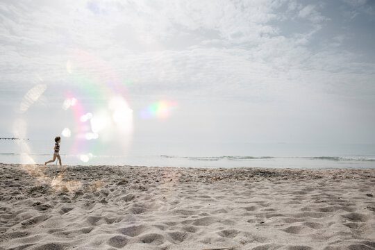 Boy running on the beach circled by a reflection created with a circular object