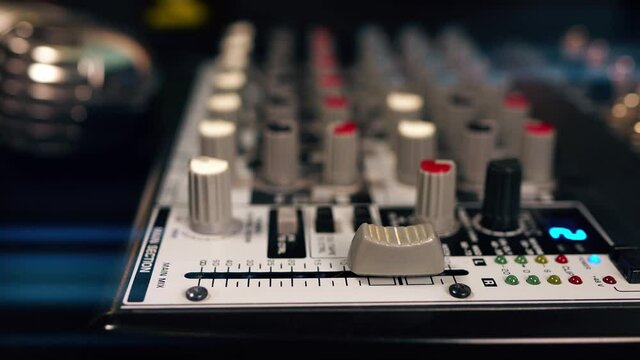 Sound engineer using main control fader of studio mixer.