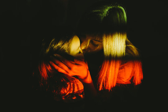 Mother kissing her daughter in the floodlight