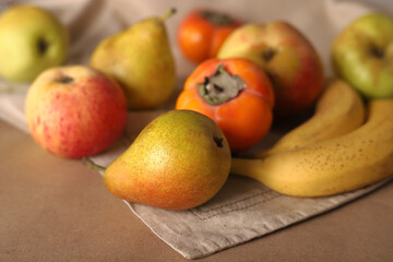 Juicy ripe fruits pears bananas apples persimmons on a linen napkin.