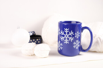 Fototapeta na wymiar Blue mug with marshmallows on a white knitted background.