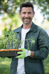 happy gardener outdoors holding pots of plants