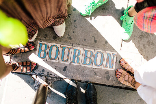 A group of people standing around the words Bourbon on the street.
