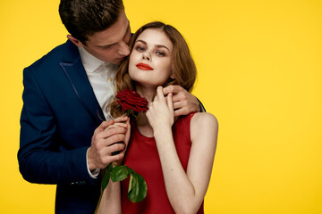 lovers man and woman with a red rose in their hands hugging on a yellow background romance relationship love family