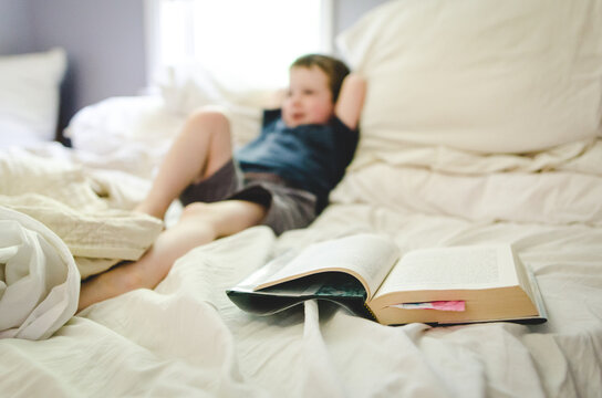 Child lying in bed beside open chapter book