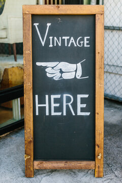 A chalkboard stand with ""vintage Here"" drawn on it.