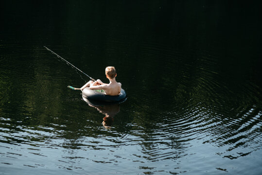 child on float in lake with fishing rod