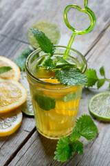 Citrus orange cold drink with mint on an old wooden background with mint and slices of lime and lemon.