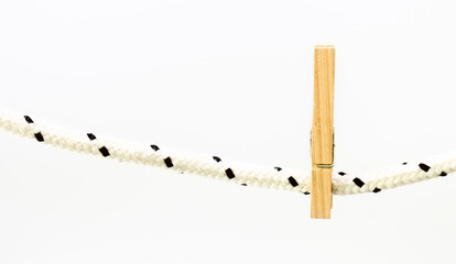 Vista frontal de broches de madera para colgar la ropa de la lavandería sosteniéndose de una cuerda aislados en un fondo blanco y luminoso. Utilizar material reciclable para las tareas domésticas.
