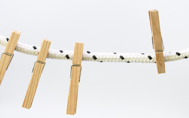 Vista frontal de broches de madera para colgar la ropa de la lavandería sosteniéndose de una cuerda aislados en un fondo blanco y luminoso. Utilizar material reciclable para las tareas domésticas.