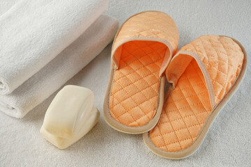 shower set in the hotel two white terry towels, soft peach slippers and two pieces of fragrant soap on a white terry mat