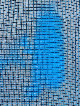 Blue graffiti paint on blue screen mesh, close up
