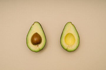 Avocado halves on beige background. Flat lay.