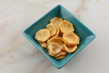 Sweet and spicy garlic wheat crisps in blue snack bowl on table