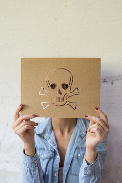 Unrecognizable person holding paperboard with carved skull