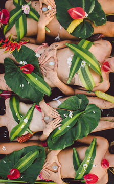 Beautiful hippie women group laying on the beach covered by plant and flowers holding healing crystal
