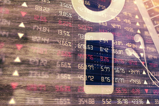 Double exposure of forex chart hologram over desktop with phone. Top view. Mobile trade platform concept.