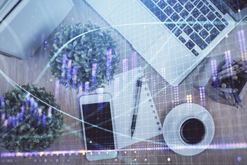 Multi exposure of financial chart hologram over desktop with phone. Top view. Mobile trade platform concept.
