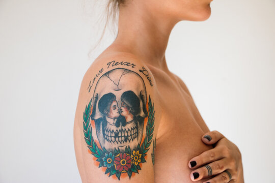 Portrait detail of woman with skull tattoo on her shoulder