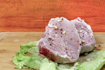 seasoned meat steak, a couple of pieces lay on a green leaf and on a wooden background