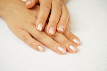 beautiful female hands with well-groomed manicure lie on a white terry towel