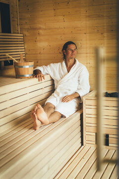 Young man in white bathrobe sits in a heated sauna enjoying the detoxofying effects at the Spa resort