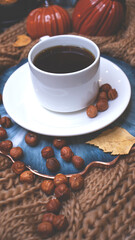 Autumn background with coffee, knitted scarf, pumpkin. Autumn coffee, dry leaves. Season October, November.