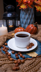 Autumn background with coffee, knitted scarf, pumpkin. Autumn coffee, dry leaves. Season October, November.